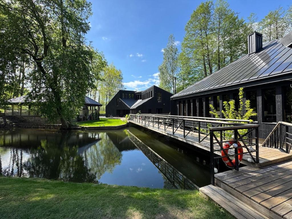 ein Gebäude mit einer Brücke neben einem Fluss in der Unterkunft Vila Strėva in Kozelkiskes