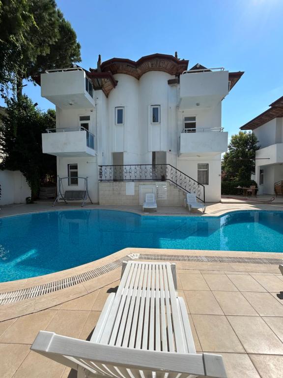 a swimming pool with a white bench in front of a building at Double Comfort Marmaris in Marmaris