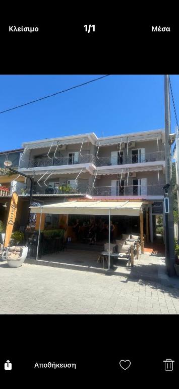 a large building with tables and benches in front of it at menidistudios in Menídion