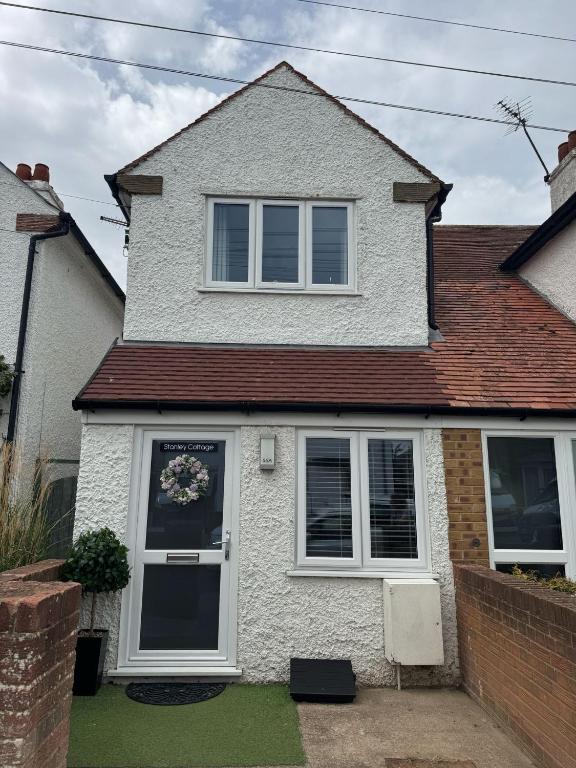 a white house with a door and windows at Stanley Cottage in Herne Bay