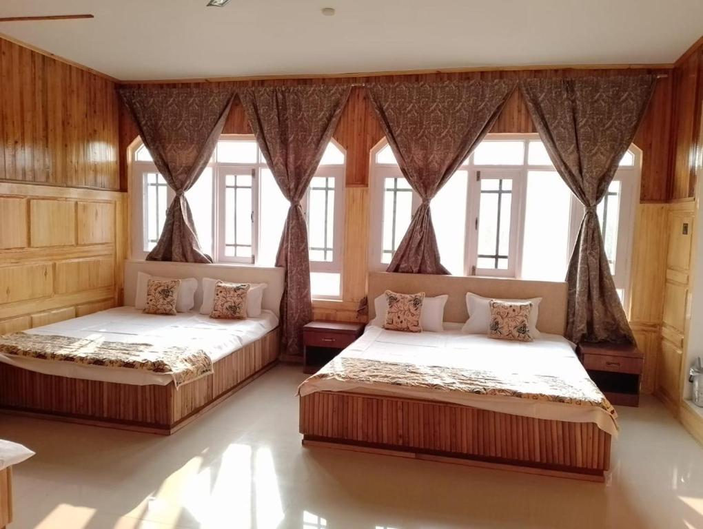 two beds in a large room with windows at Rooebarpur in Khāniyār