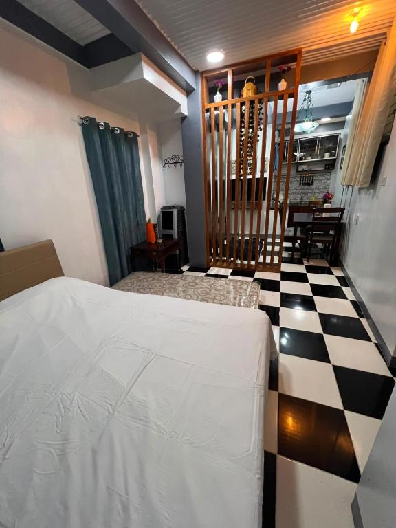 a bedroom with a bed and a black and white checkered floor at Tiya Cheding Boarding House in Carolina