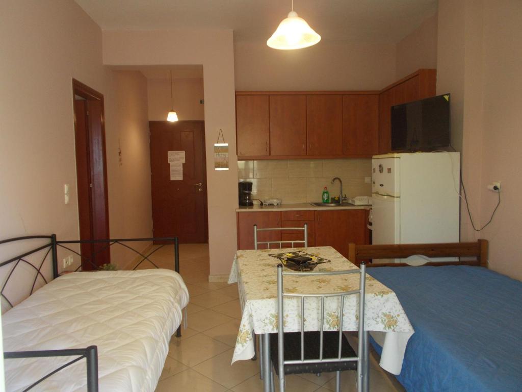 a kitchen with two beds and a table and a refrigerator at Διαμέρισμα τεσσάρων ατόμων in Filiatra