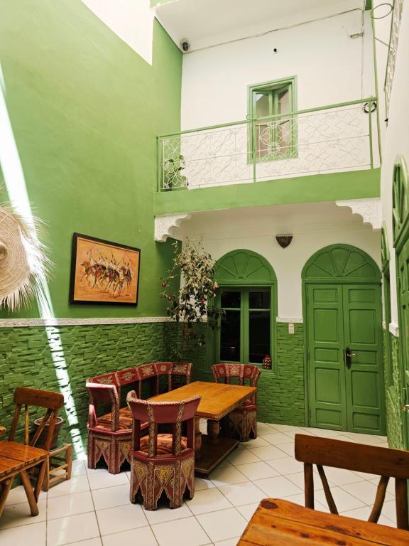 a dining room with green walls and a wooden table and chairs at Dar Suncial in Marrakesh