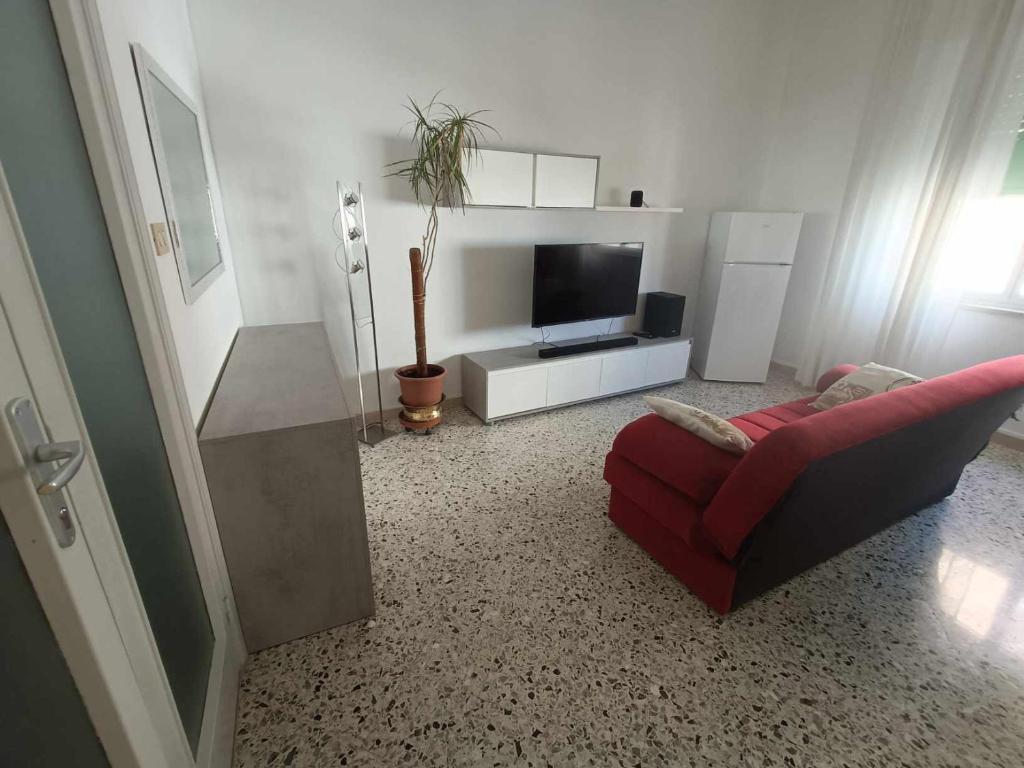 a living room with a red couch and a television at Sant' Agostino Suite in Trapani