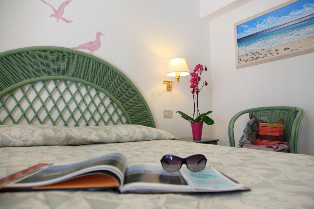 a bed with a book and sunglasses on it at Eco Hotel Montemerlo in Fetovaia