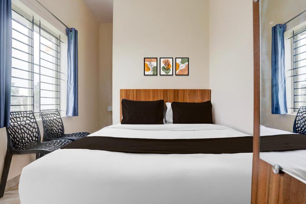 a bedroom with a large white bed and two windows at Hotel O by OYO Saptagiri Comforts in Bangalore