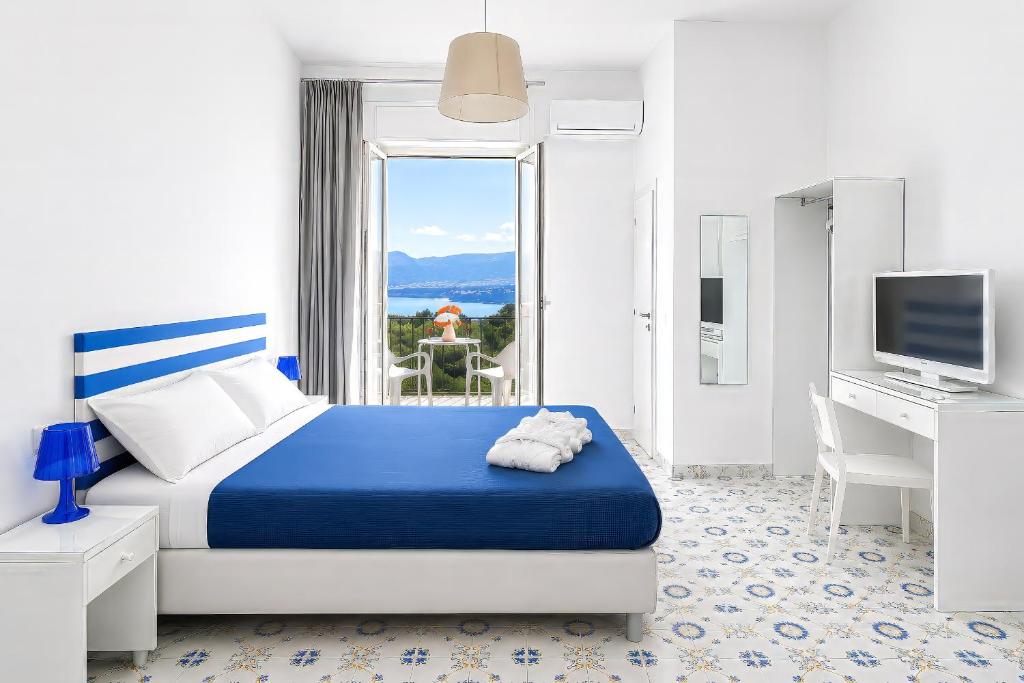 a bedroom with a blue and white bed and a window at Hotel Spicy in Sorrento