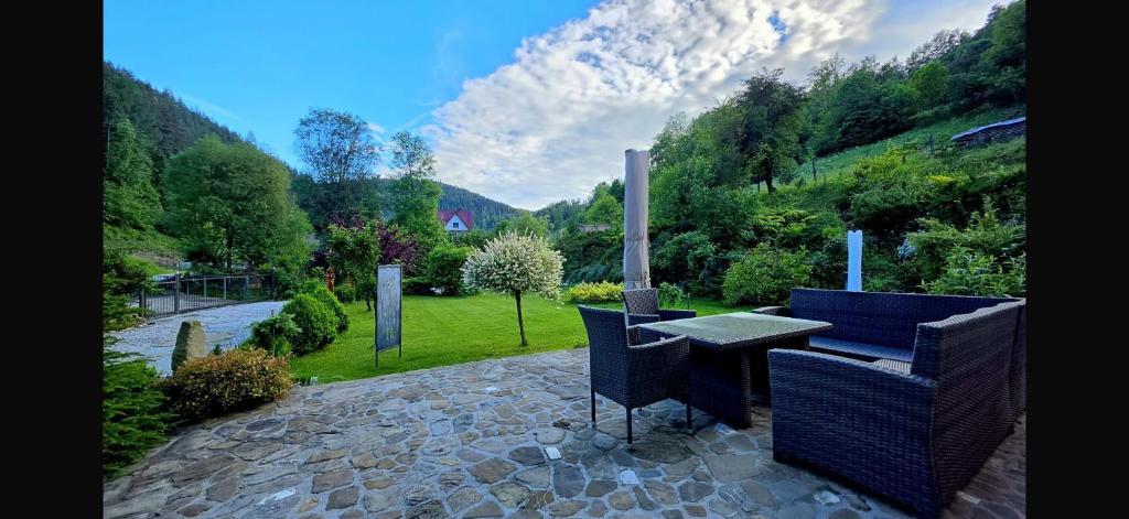 a patio with a table and chairs in a garden at Nad Strumykiem APARTAMENT in Ochotnica Dolna