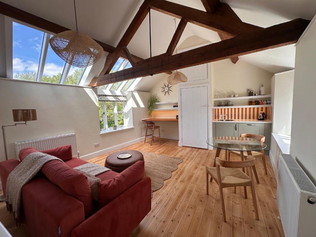 a living room with a red couch and a table at Hinton Hayloft in Hinton in the Hedges
