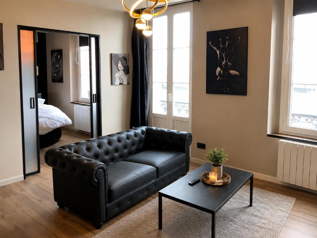 a living room with a black leather couch and a table at Pas Sages in Le Tréport