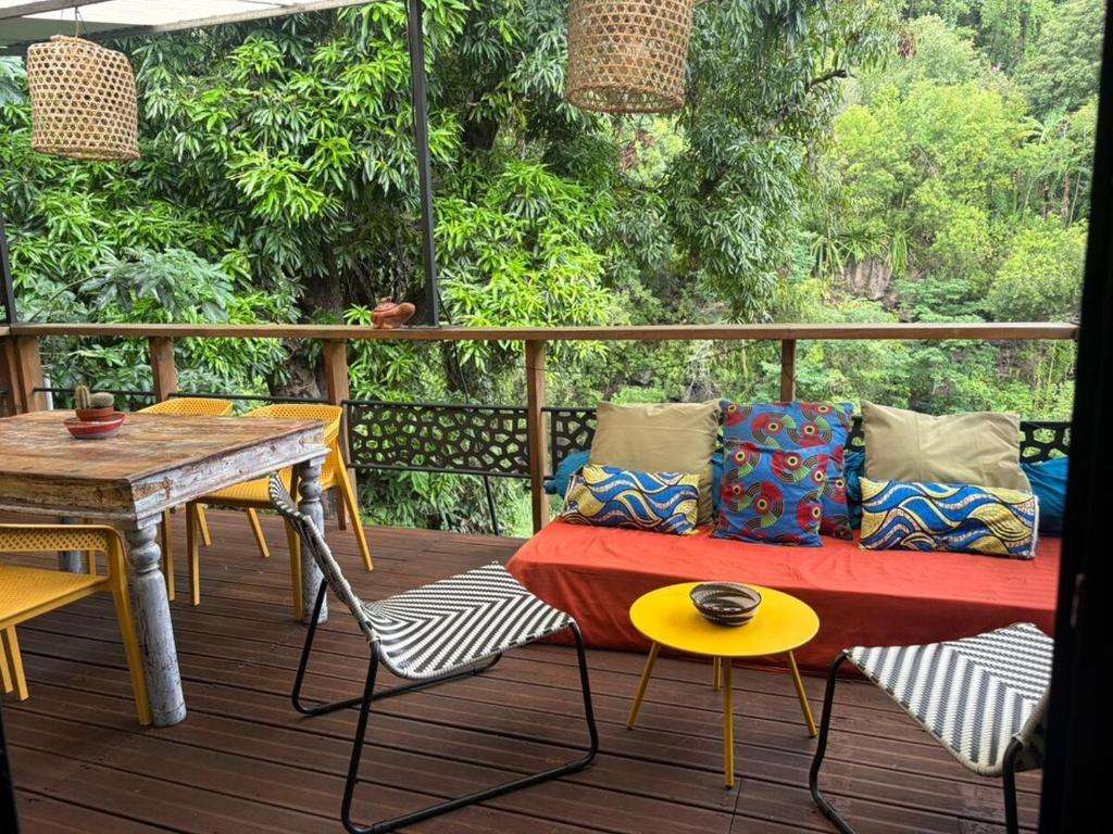 a couch on a deck with a table and chairs at River House superbe vue- vue et accès directe sur la rivière et baignade dans les bassins naturels in Saint-Joseph