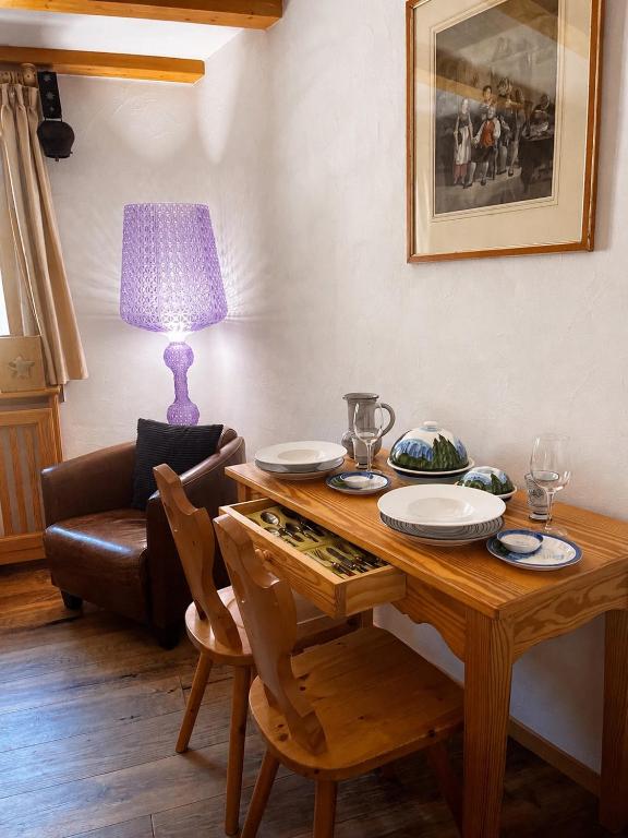 a wooden table with chairs and a lamp in a living room at Bijou Alpina Surlej in Silvaplana