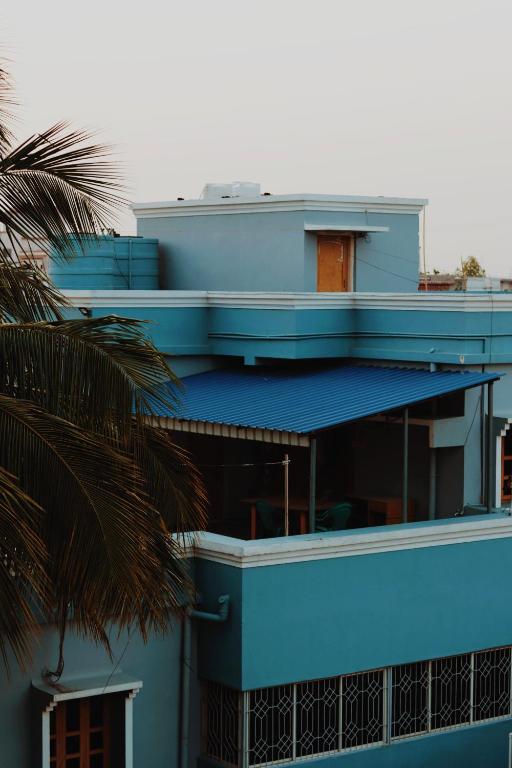 a blue building with a blue roof and a palm tree at The Olive County in Thirumurugan Poondi