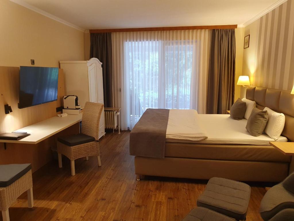 a hotel room with a large bed and a desk at Hotel Garni Eichhornkobel in Faßberg