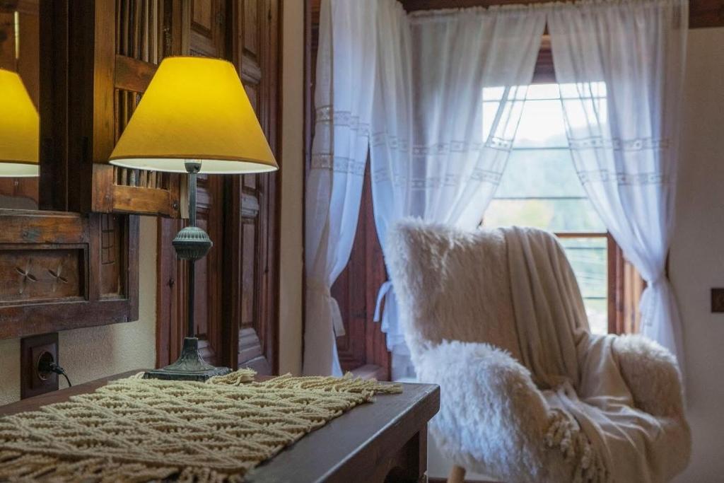 a table with a lamp and a chair and a window at Конак Буката in Bukata