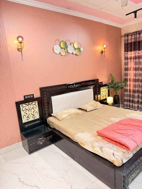 a bedroom with a bed in a room with pink walls at Meraki Homes in Karnal