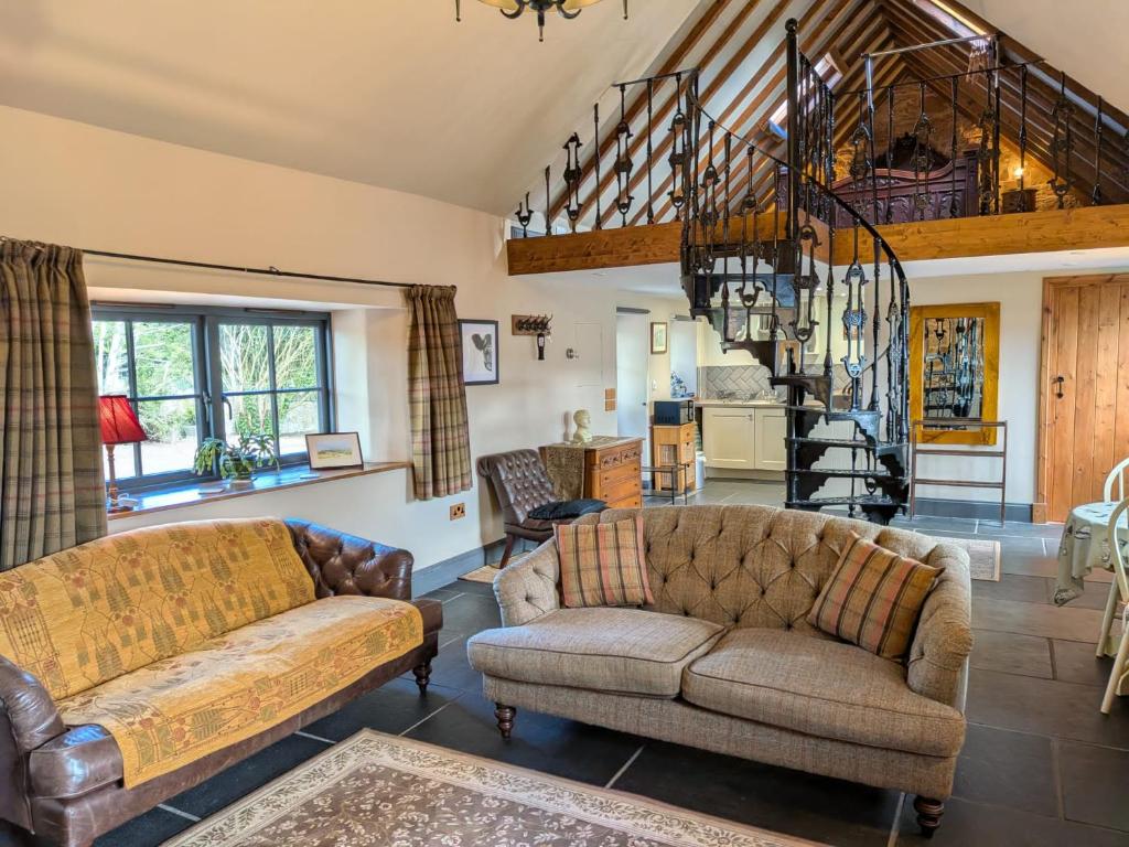 a living room with two couches and a staircase at Stable Lodge in Berwick-Upon-Tweed