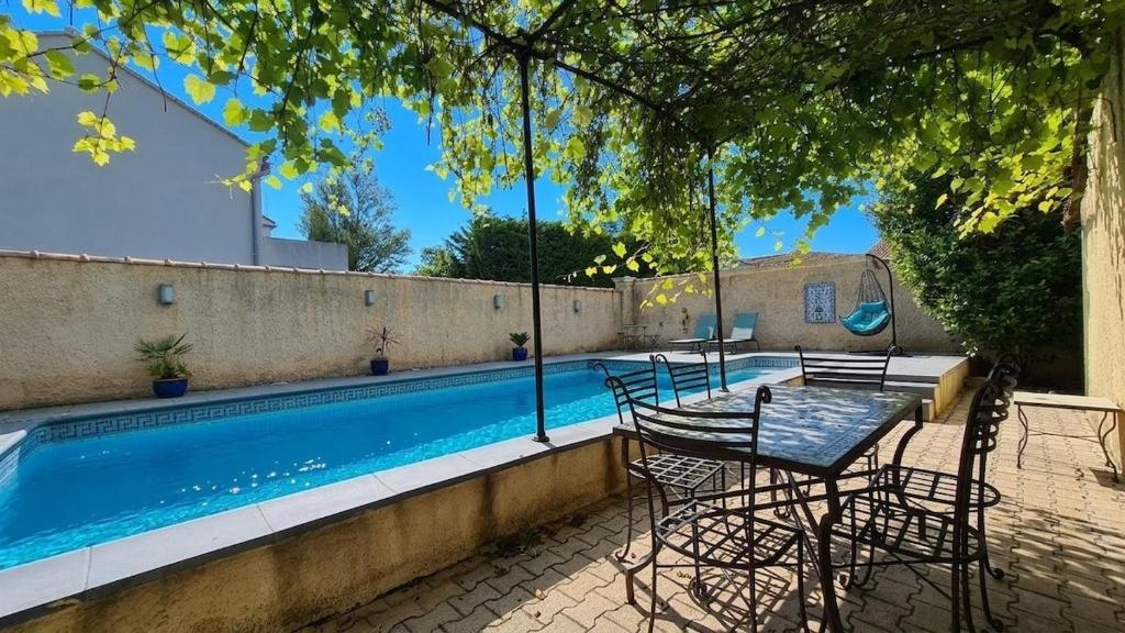 a patio with a table and chairs next to a swimming pool at La Santoline - Provençal break with pool in Le Thor