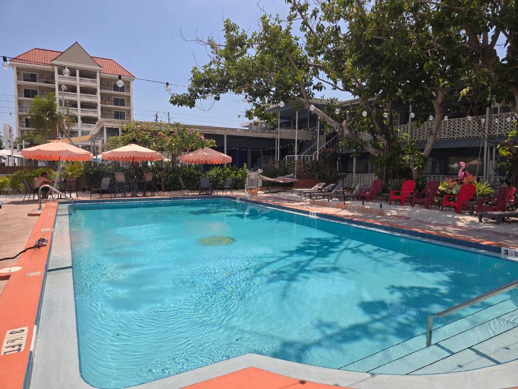 a large swimming pool in a hotel with chairs and umbrellas at Malibu Resort Motel in St. Pete Beach