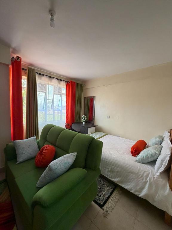 a living room with a green couch and a bed at Tulivu House in Embu