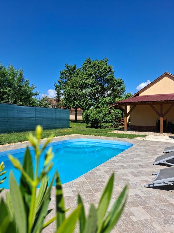 a swimming pool with two chairs and a gazebo at Potyka Apartman in Tiszafüred