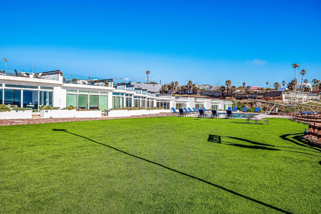 a large field of grass in front of a building at Dog-friendly home 3 rows to beach with rooftop deck, pool, hot tub, & kitchen in Rosarito