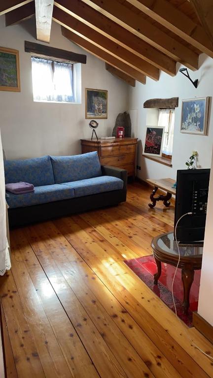 a living room with a blue couch and a wooden floor at RIVER resort in Varallo