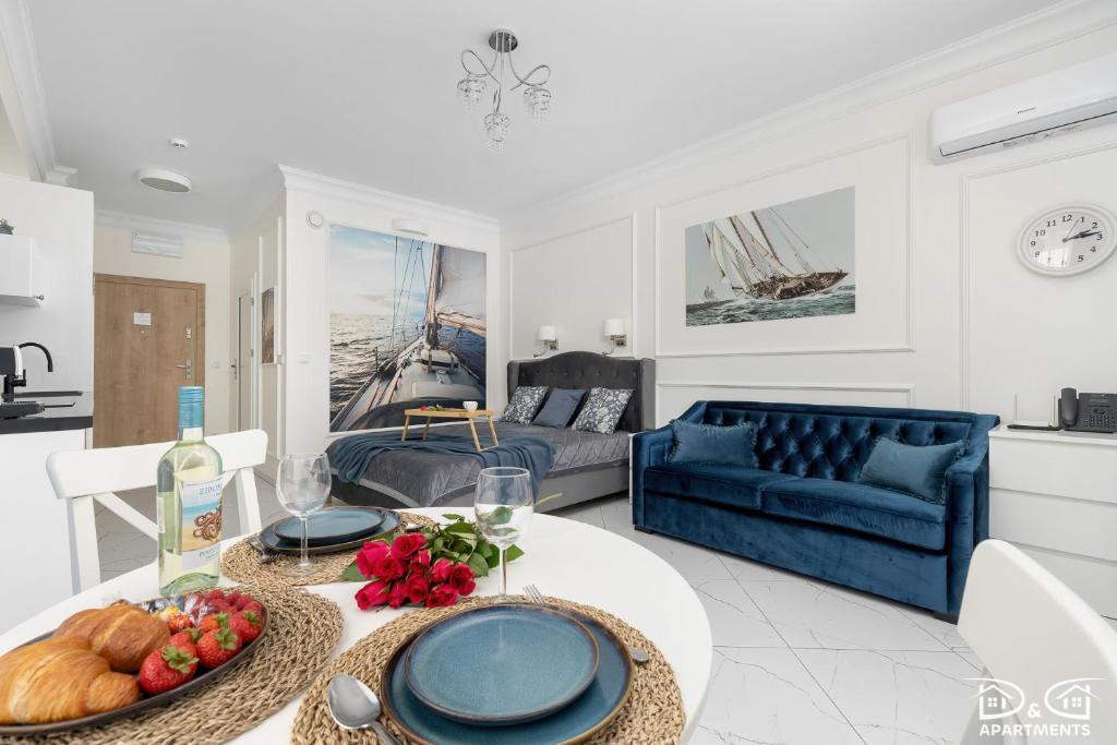 a living room with a table and a blue couch at Marítimo D&D Apartments Porta Mare in Dziwnówek