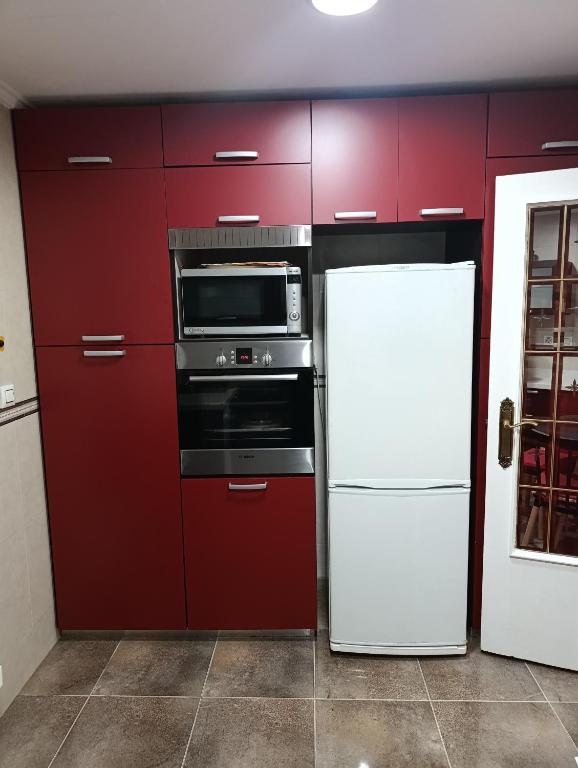 a kitchen with red cabinets and a white refrigerator at Aroca in Elda