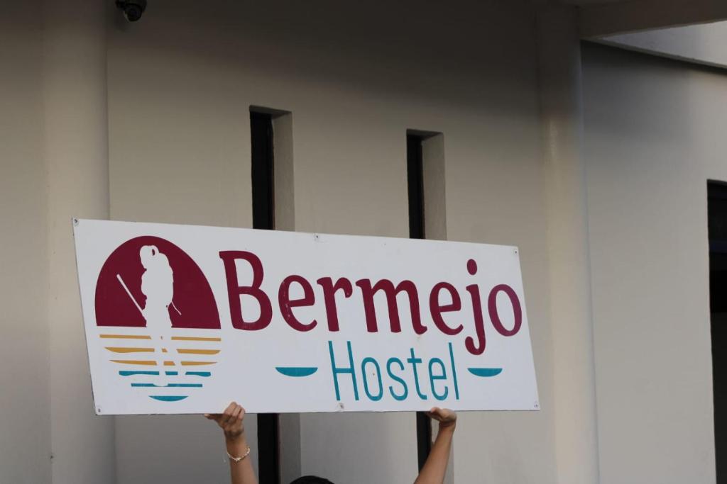 Eine Person hält ein Schild mit der Aufschrift „Bennero Hostel“. in der Unterkunft Bermejo Hostel LAP in La Paz