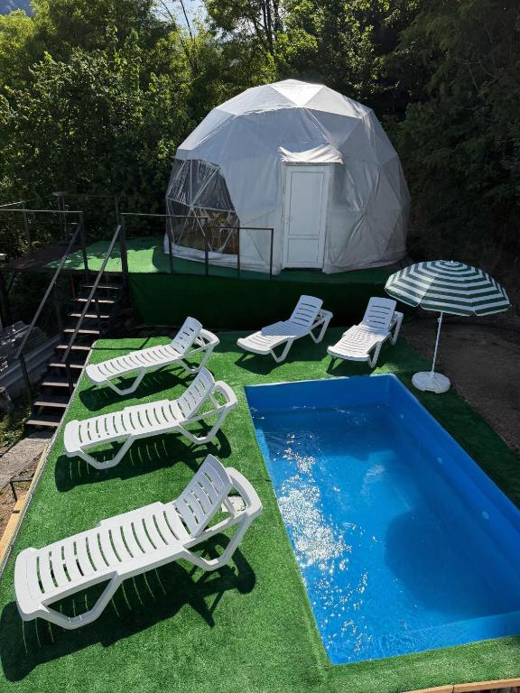 a group of lawn chairs and a tent with a swimming pool at Mtirala Yurt in Batumi