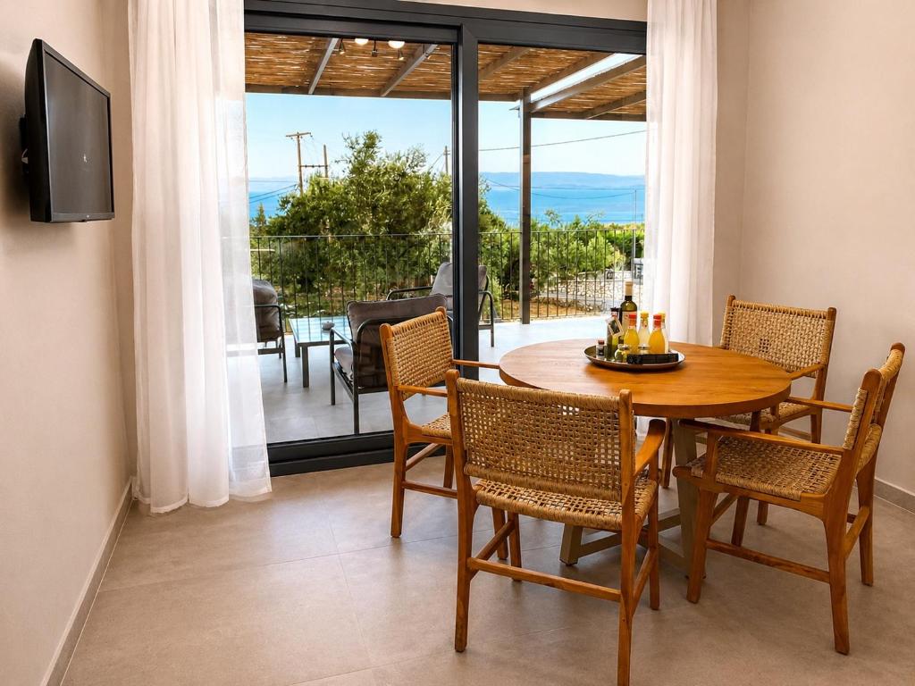 a dining room with a table and chairs and a balcony at Spitaki Among Olives in Tsoukalades