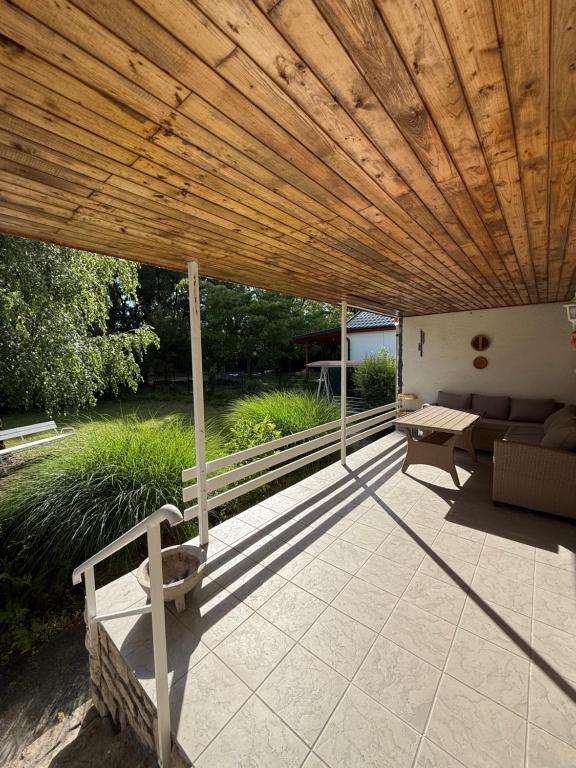 a wooden roof over a patio with a couch and a table at Hegylakó vendégház in Balatonkenese