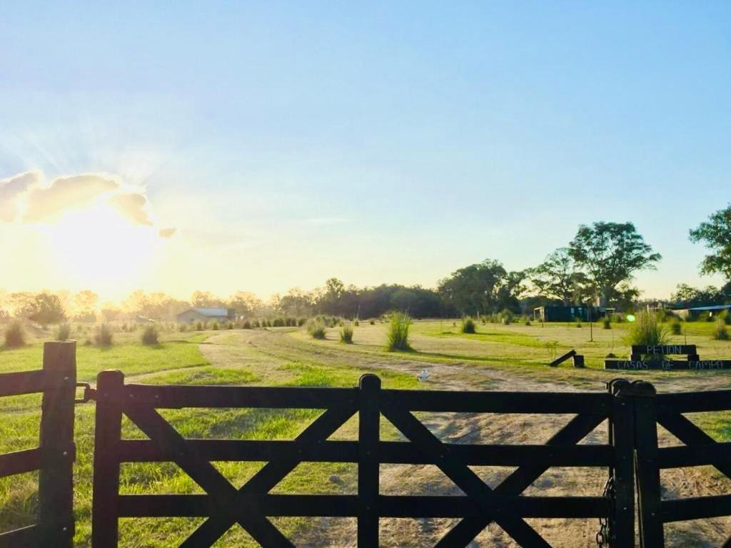 a fence in a field with the sun in the background at Petion Polo Ranch in Cañuelas