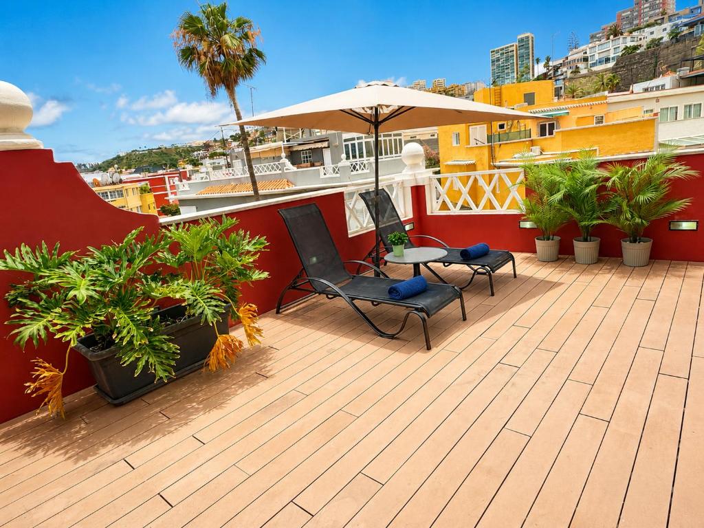 a balcony with two chairs and an umbrella and plants at Deluxe Coliving Islas Canarias in Las Palmas de Gran Canaria