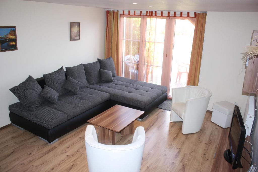 a living room with a black couch and white chairs at zum Sanddorn in Saal
