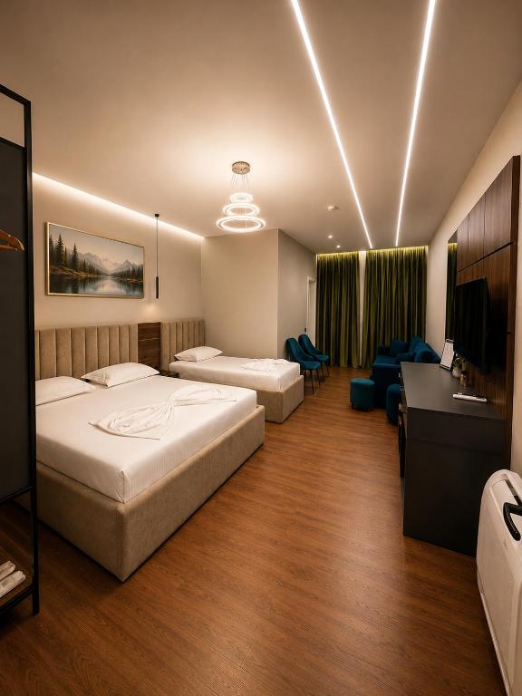ein Hotelzimmer mit zwei Betten und einem Schreibtisch und einer Couch in der Unterkunft Hotel Muja in Rinas