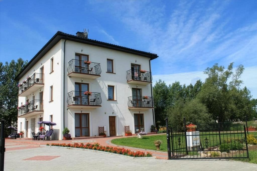 a white building with balconies and a yard at Pensjonat nad Stawem in Sarbinowo