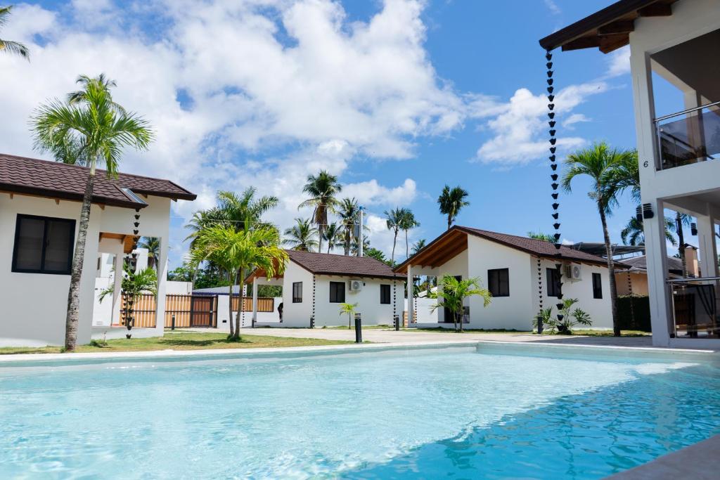 a swimming pool in front of a house with palm trees at Solaris Villa in Las Terrenas