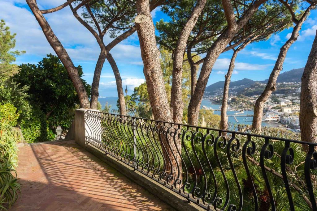 a fence with trees and a view of a city at Villa Le Pagine Bianche in Lacco Ameno