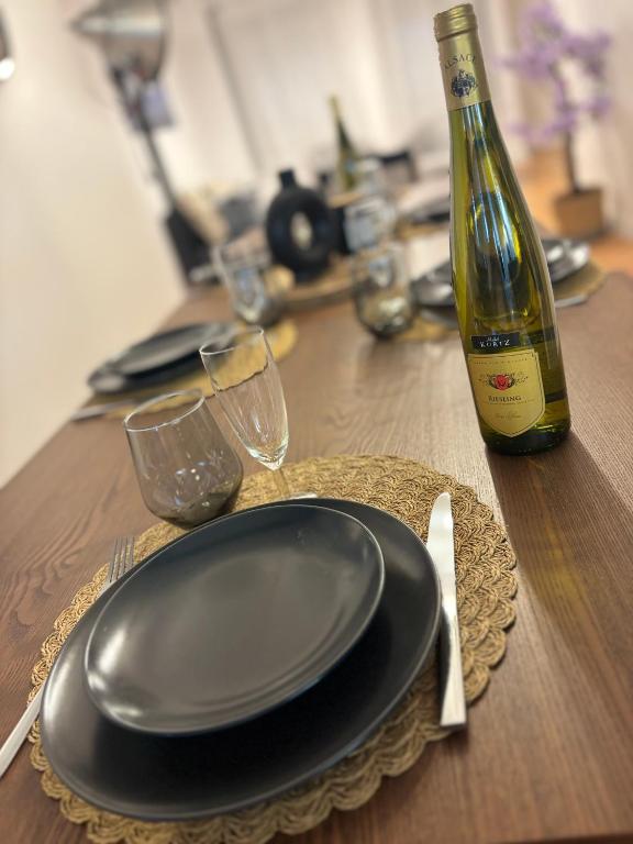 a table with a black plate and a bottle of wine at Le flocmagny in Chalons en Champagne