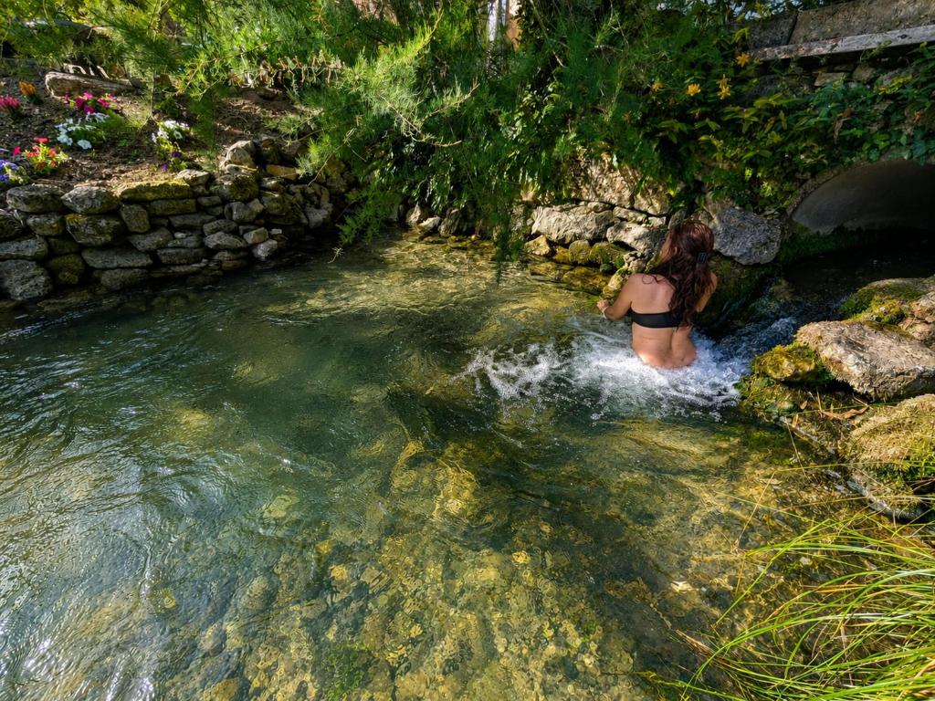 a woman in a bathing suit in a river at Gîte du Domaine du Moulin de la Roque in Castels