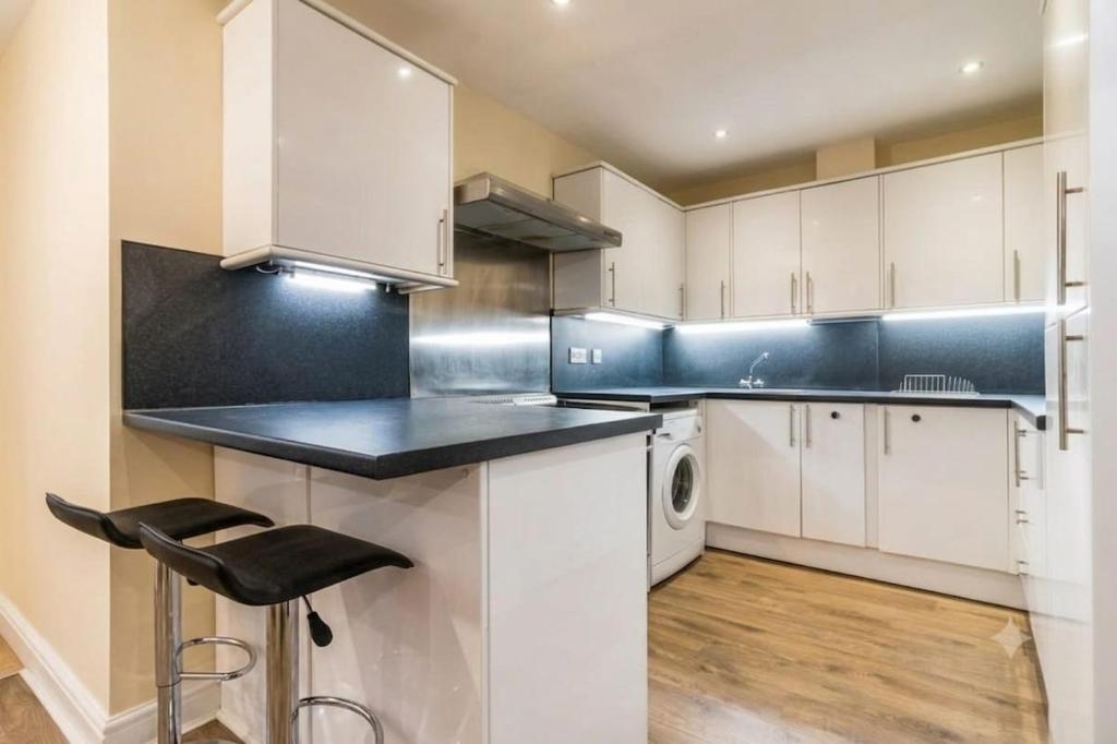 a kitchen with white cabinets and a black counter top at Central 2 bed large apt M1 area in Manchester