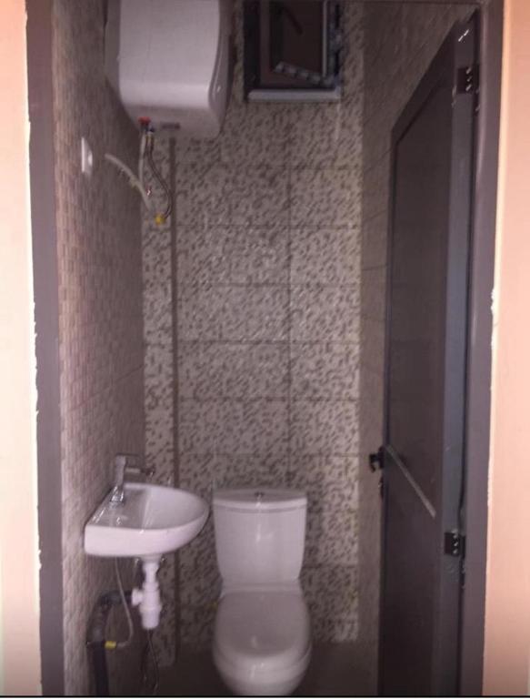 a small bathroom with a toilet and a sink at Immeuble Racine in Ngaparou