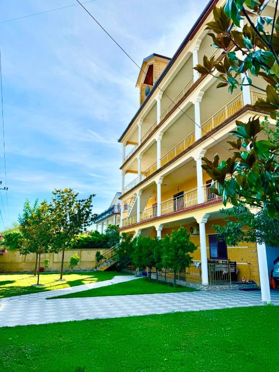 a large building with a green lawn in front of it at Colombo' s House in Shkodër