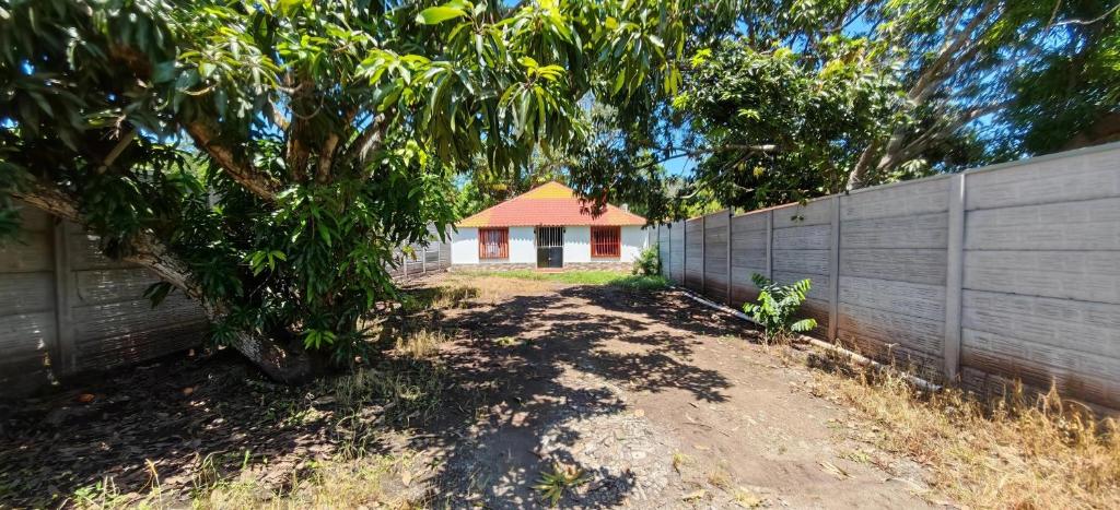 a house behind a fence with a tree at Rancho Amigos Columbias Caldera in Esparza