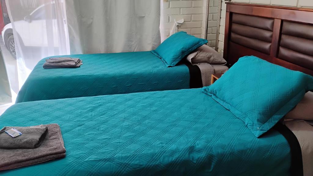 two beds in a room with blue sheets and towels at Hostal Donde Rita in Vicuña