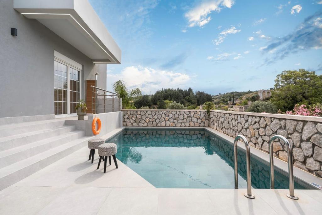 a house with a swimming pool and a stone wall at Eldorado Luxury Villa in Afantou