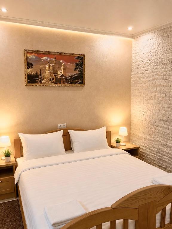 a bedroom with a large white bed with two lamps at Park Hotel in Uman